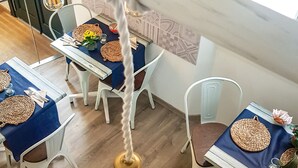 A dining area with round tables, white chairs, and a hanging light fixture. - Hotel Romantic Los 5 Sentidos (Ciutadella de Menorca)
