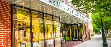 A hotel with a glass facade, outdoor seating, and a brick exterior.