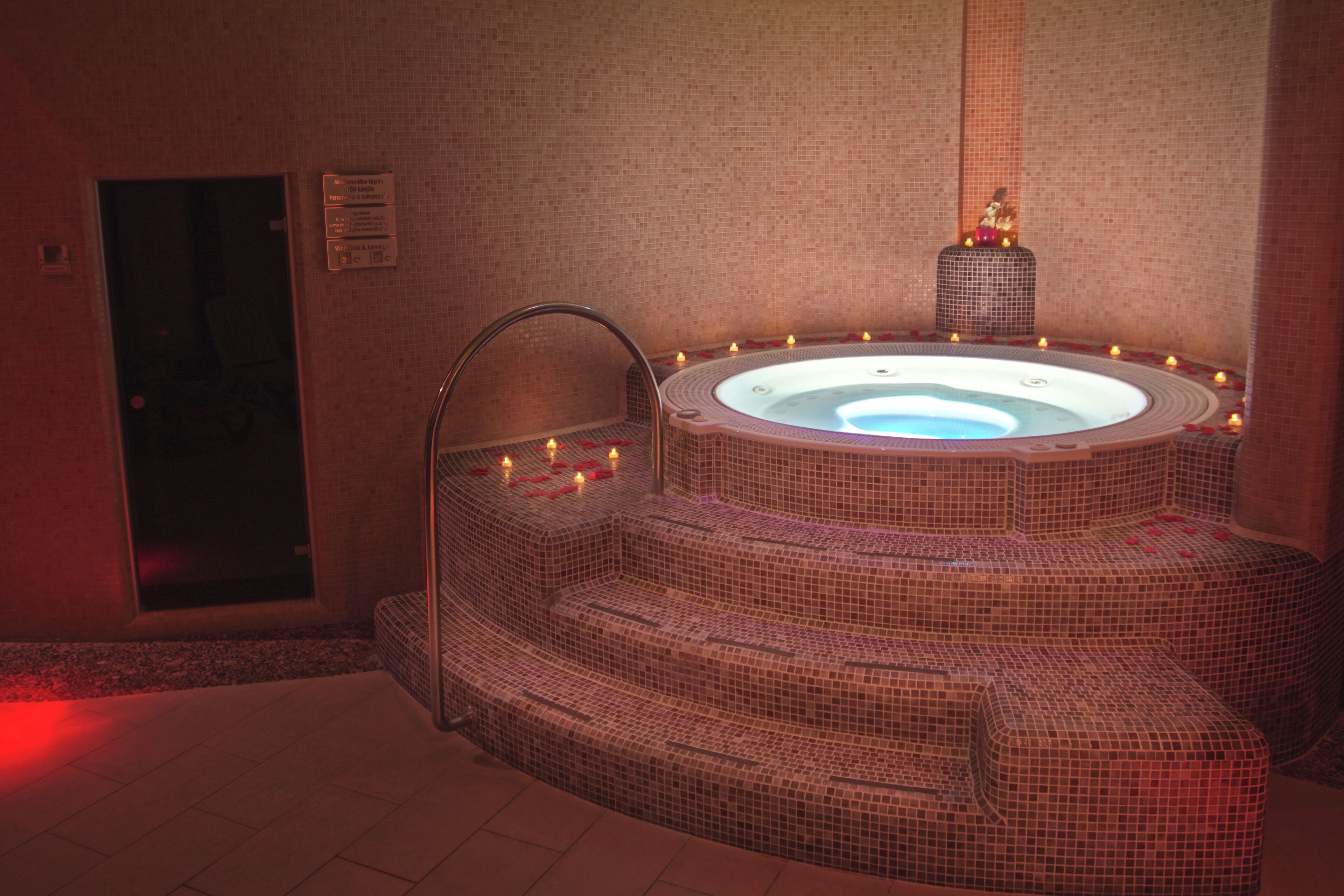 Un jacuzzi con diseño de mosaico, rodeado de escalones y velas.