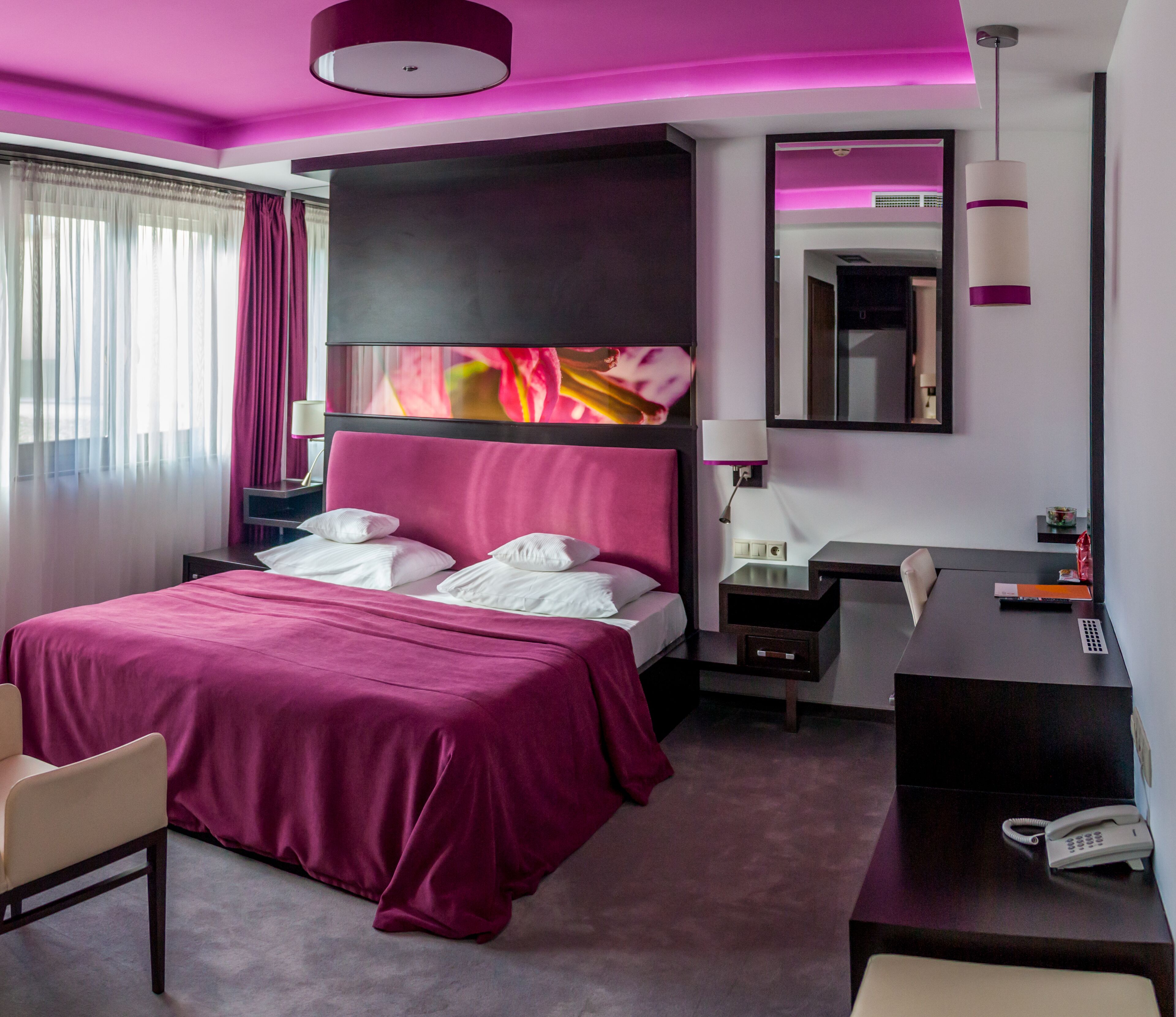 Una habitación de hotel moderna con una cama grande, un escritorio y una silla.