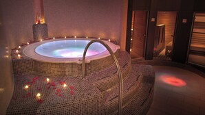A hot tub surrounded by mosaic tiles, with candles and rose petals on the floor. - Corso Boutique Hotel (Gyula)