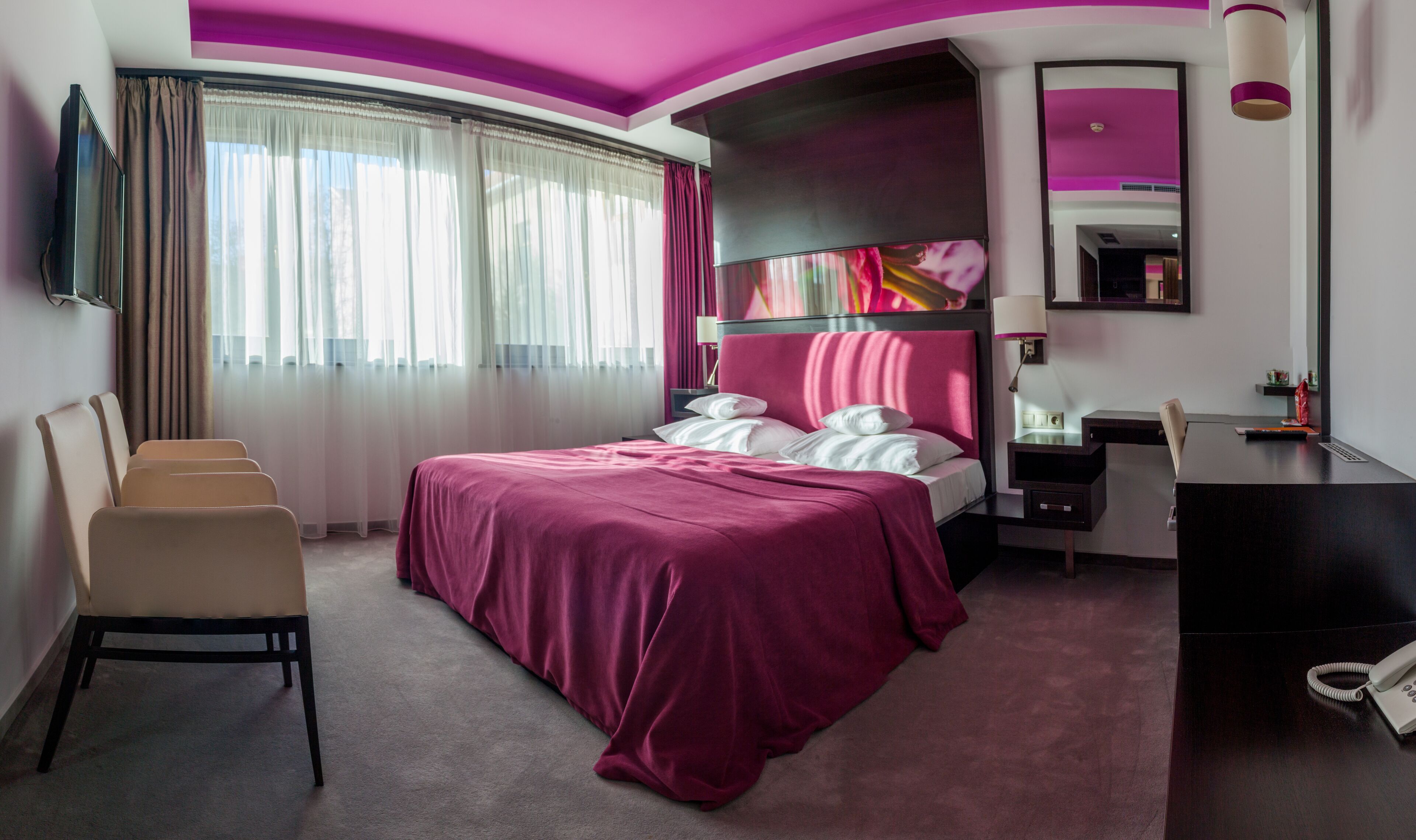 Una habitación de hotel con una cama grande, un escritorio, una silla y un televisor.