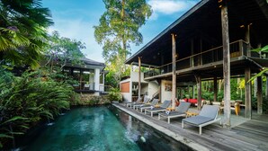 A pool area with lounge chairs and a wooden deck. - Surya Kembar Villas (Ubud)