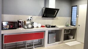 A kitchen with a microwave, stove, sink, and a red cabinet. - Damai at Atlantis Residences Melaka (Malacca City)