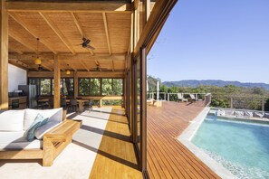 Une terrasse en bois avec une piscine, un canapé et un coin repas offrant une vue sur un paysage montagneux.