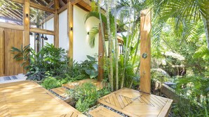 A wooden deck with a thatched roof, surrounded by lush tropical plants and a wooden fence. - Luxury Villa Melody- Santa Teresa beach  (Playa Santa Teresa)