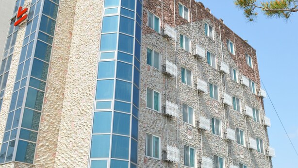 A multi-story building with a stone facade and large windows.