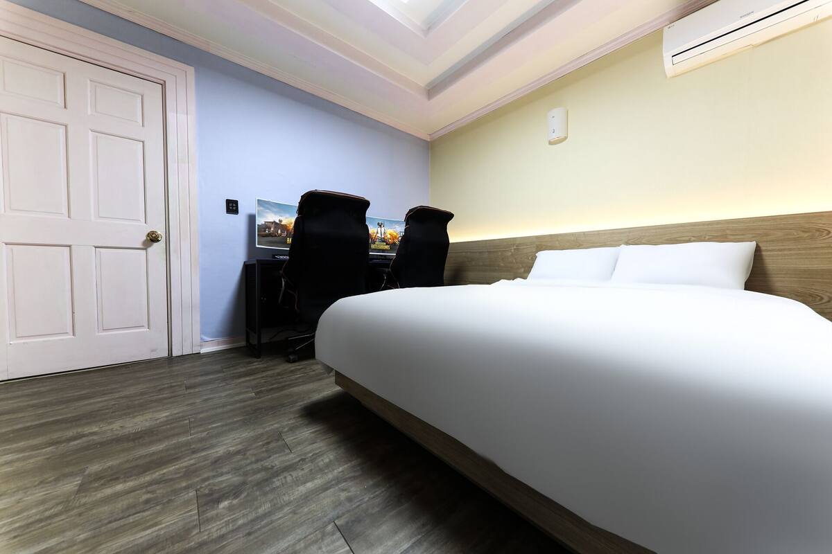 A hotel room with a large bed, a desk with a computer, and a chair.