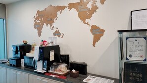 A reception desk with a world map, coffee machines, a bread display, and a framed certificate.