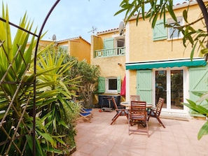 A patio with outdoor furniture and a sliding glass door leading to a covered area. - Cozy 3-Bedroom Villa with A/C, Terrace, and BBQ – 350m from Beach in Narbonne-Plage (Narbonne-Narbonne Plage-Narbonne Plage)