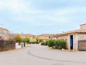 Une rue résidentielle tranquille, bordée de maisons aux toits de tuiles, avec une entrée fermée par un portail et un panneau indiquant qu’il s’agit d’une propriété privée.