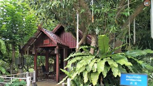 A traditional wooden structure with a covered porch, surrounded by lush greenery and potted plants. - Phetsangsom Resort (Klaeng)
