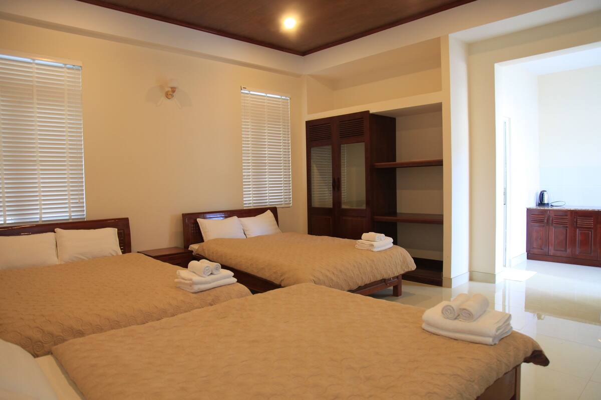 A hotel room with two beds, a wardrobe, and a bathroom visible through an open door.