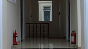 A clean, well-lit entrance with a tiled floor, a wooden railing, and fire extinguishers on either side. - Oscar House (Xuan Huong - Da Lat)