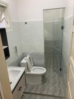 A bathroom with a toilet, sink, and glass shower enclosure. - Oscar House (Xuan Huong - Da Lat)