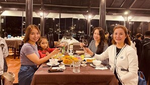 A group of people dining at a restaurant with a view of the city at night. - Oscar House (Xuan Huong - Da Lat)