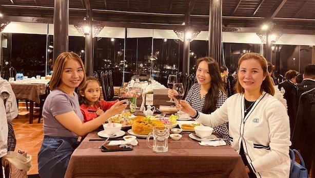 A group of people dining at a restaurant with a view of the city at night. - Oscar House (Xuan Huong - Da Lat)