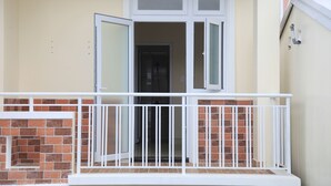 A balcony with white railings and a brick wall. - Oscar House (Xuan Huong - Da Lat)
