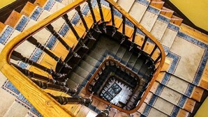 A spiral staircase with a wooden handrail and a checkered floor pattern. - Hotel Cantábrico de Llanes (Llanes)