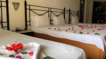 A hotel room with two beds, a nightstand, a phone, and a mirror.