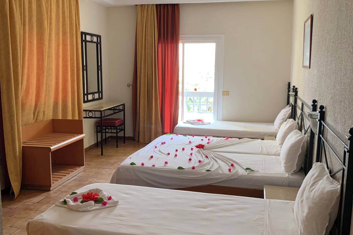 A hotel room with two beds, a desk, a chair, and a balcony.