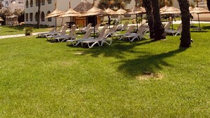 A resort with a white building, palm trees, and sun loungers. - Sol Palmeras Beach - Family Hotel (Sousse)