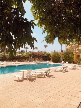 Una piscina al aire libre de temporada, sombrillas