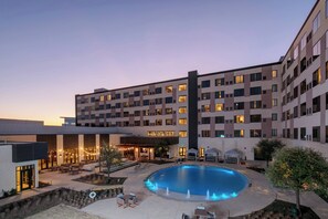 Enjoy a refreshing swim in our courtyard pool surrounded by lush greenery and comfortable outdoor seating.