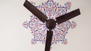 A ceiling fan with a decorative floral pattern and a ceiling with a geometric design. - Rising Shemesh (Udaipur)