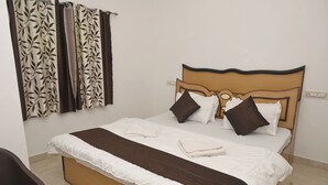 A single bed with a wooden headboard, white and brown bedding, and two brown pillows. - Rising Shemesh (Udaipur)
