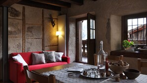 A cozy room with a red sofa, a wooden table with a tray of nuts, a bowl of nuts, and a bottle. - Dormì & Disnà (Val di Zoldo)