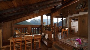 A wooden interior with a dining area, a bench, and a view of mountains. - Dormì & Disnà (Val di Zoldo)