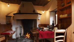 A cozy room with a fireplace, wooden furniture, and a red tablecloth. - Dormì & Disnà (Val di Zoldo)