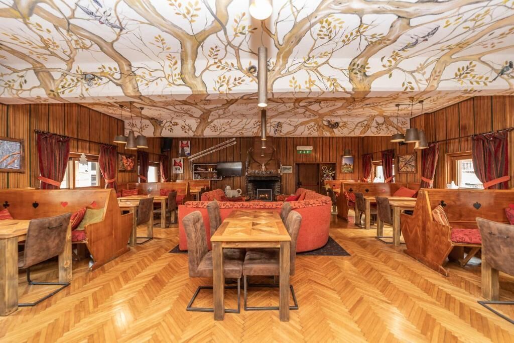 A restaurant with wooden walls, a herringbone floor, and a ceiling mural.