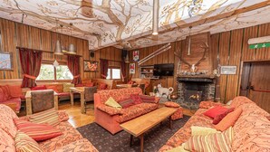 A cozy, wood-paneled room with a fireplace, comfortable seating, and a television. - Hotel Gran Baita (Sauze d'Oulx)
