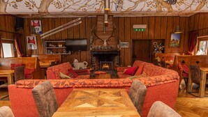 A cozy lounge area with a fireplace, wooden walls, and comfortable seating. - Hotel Gran Baita (Sauze d'Oulx)