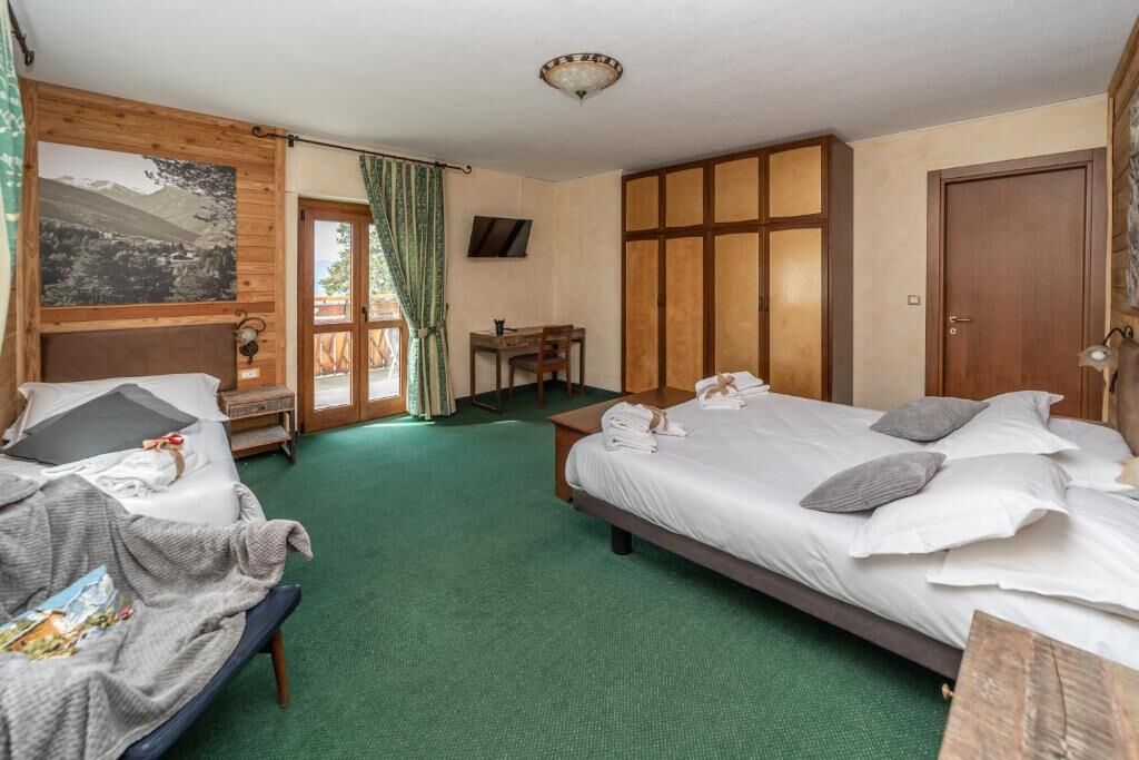 Une chambre d’hôtel avec deux lits, un bureau, une chaise et une grande fenêtre avec des rideaux.