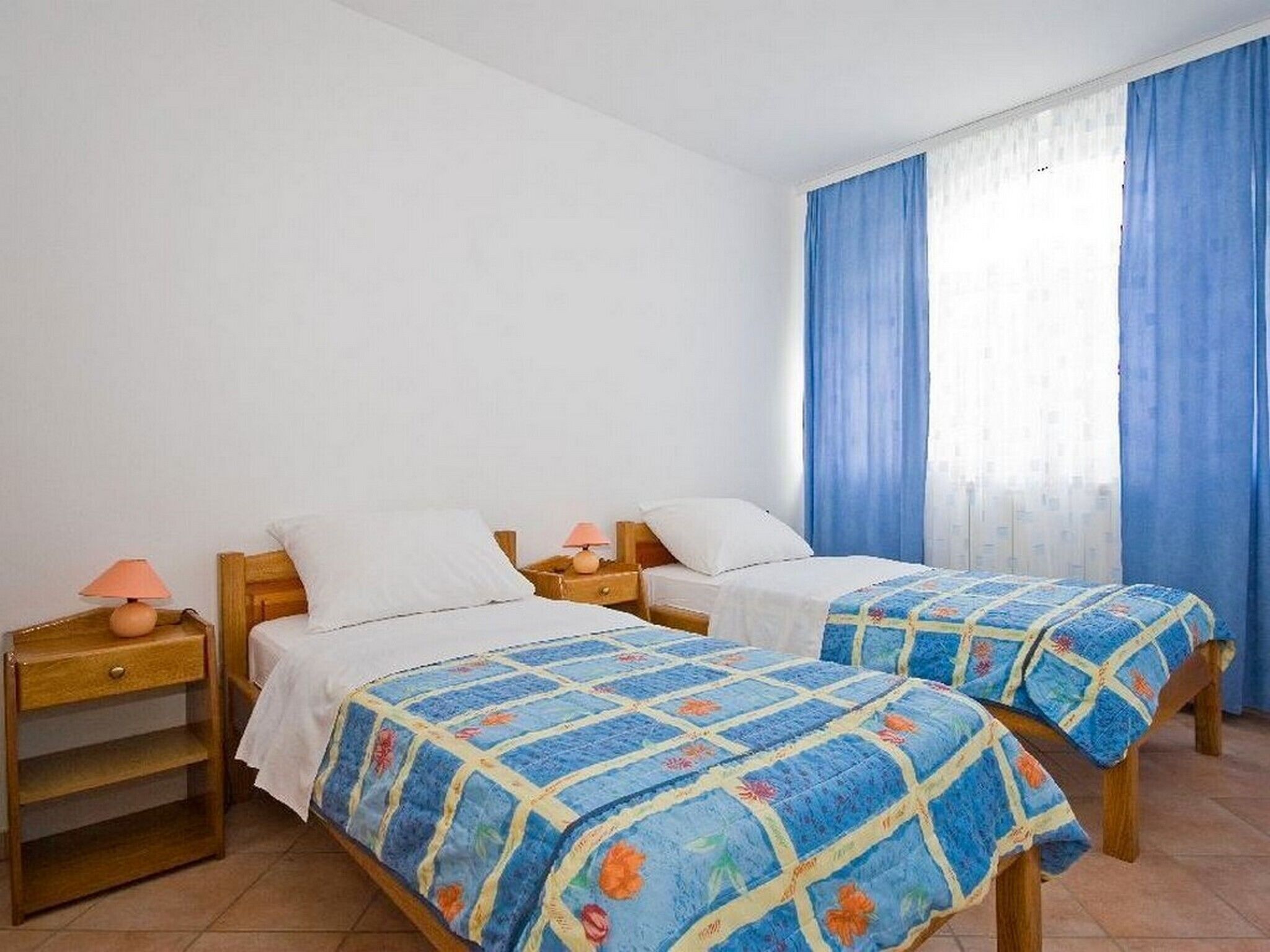Une chambre avec deux lits, chacun doté d’une tête de lit en bois et d’une table de chevet assortie.