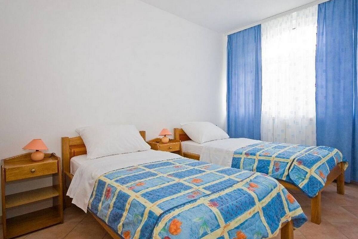 A room with two beds, each with a wooden headboard and a matching nightstand.