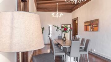 A dining area with a chandelier, a table with chairs, and a vase with flowers.