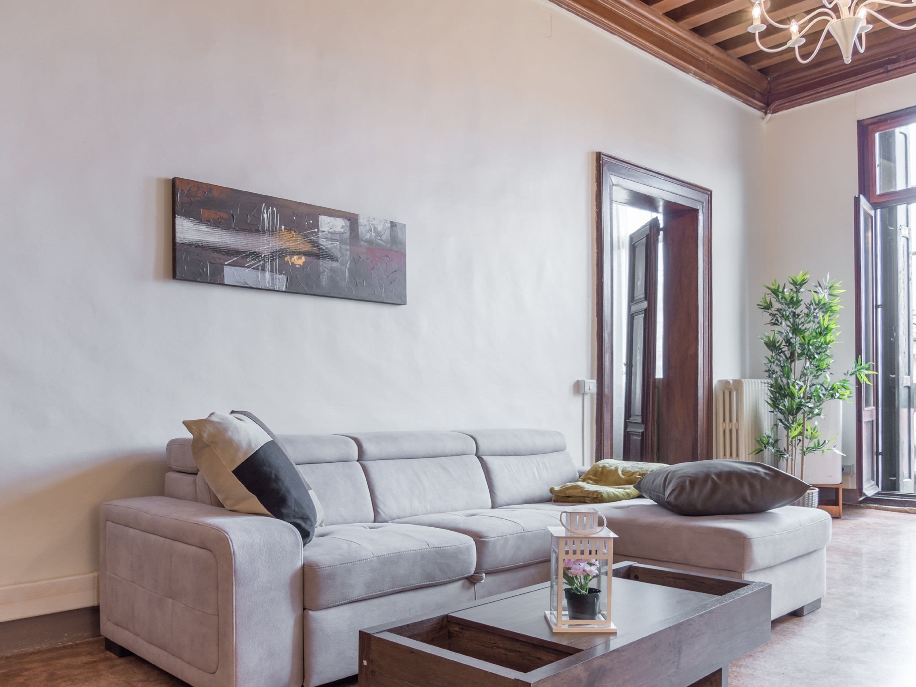 Ein modernes Wohnzimmer mit grauem Sofa, Couchtisch und einem Gemälde an der Wand.
