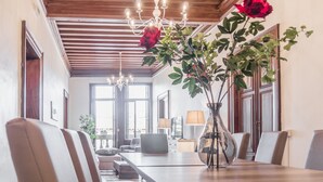A dining area with a long wooden table, multiple chairs, a vase with flowers, and a chandelier. - Riva Palace Apartments by Wonderful Italy (Venice)