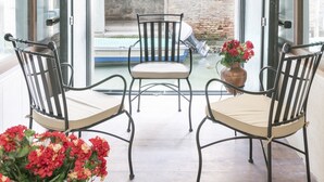 A balcony with two metal chairs and a table, overlooking a brick courtyard with an archway. - Riva Palace Apartments by Wonderful Italy (Venice)