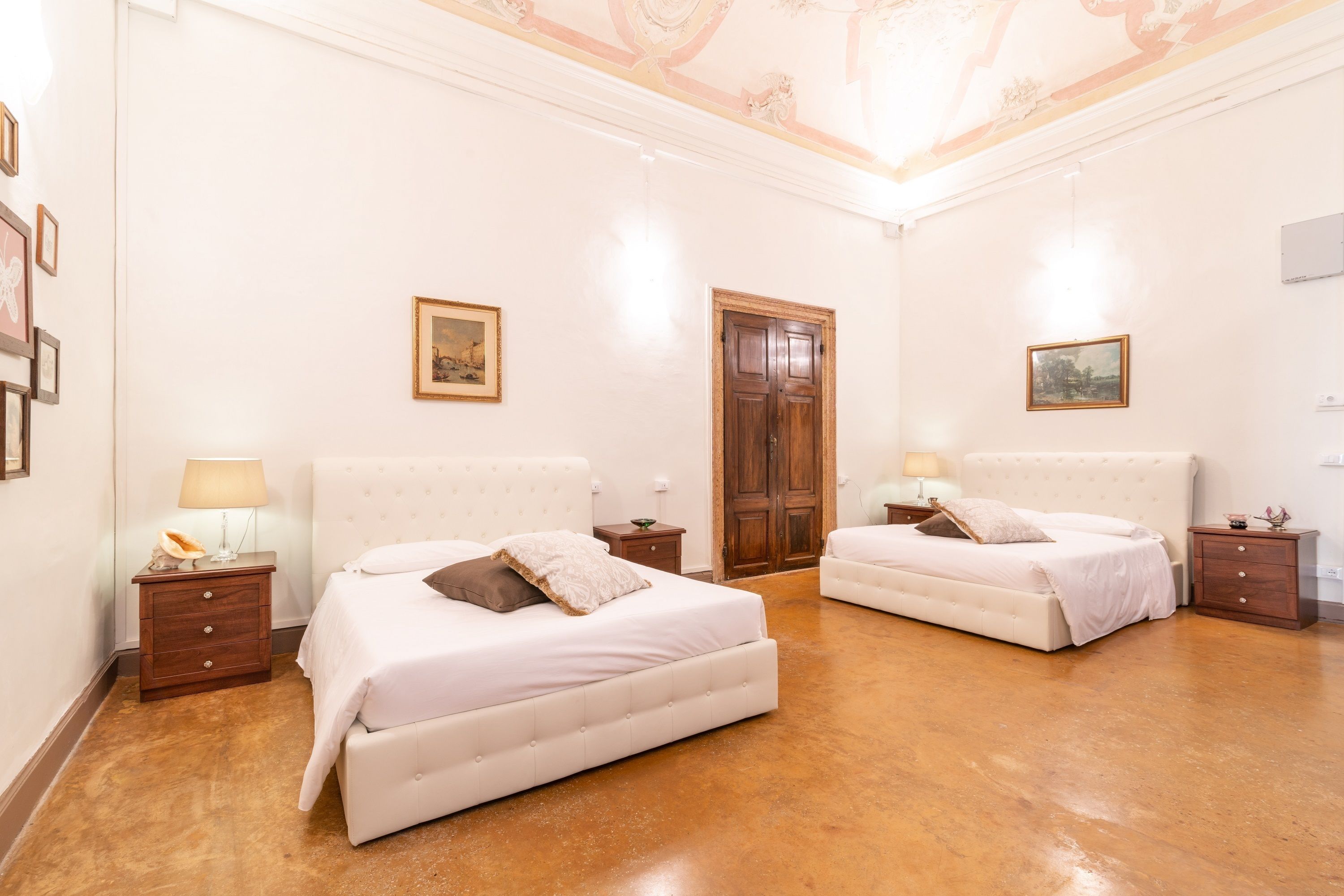 A hotel room with two beds, a wooden door, and framed pictures on the walls.