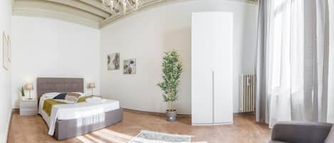 A modern bedroom with a bed, bedside tables, a potted plant, a wardrobe, and a radiator.