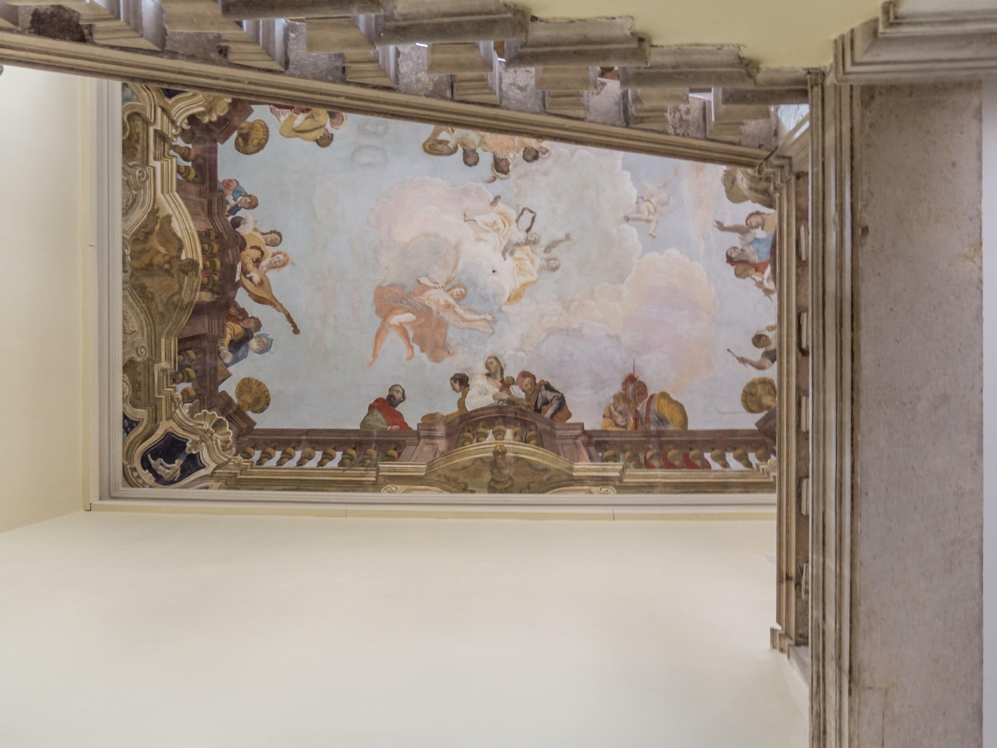 A ceiling with a classical fresco mural, ornate moldings, and a decorative cornice.