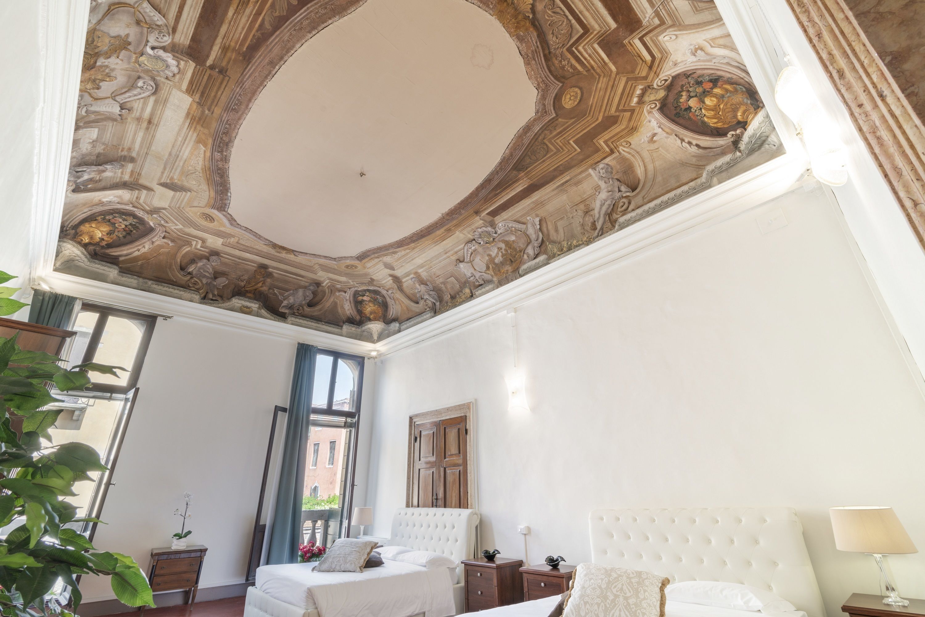 A spacious room with a large bed, a wooden door, and a ceiling with intricate designs.