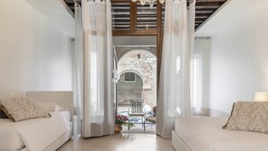 A bedroom with two beds, a view of an outdoor patio, and a stone archway. - Riva Palace Apartments by Wonderful Italy (Venice)