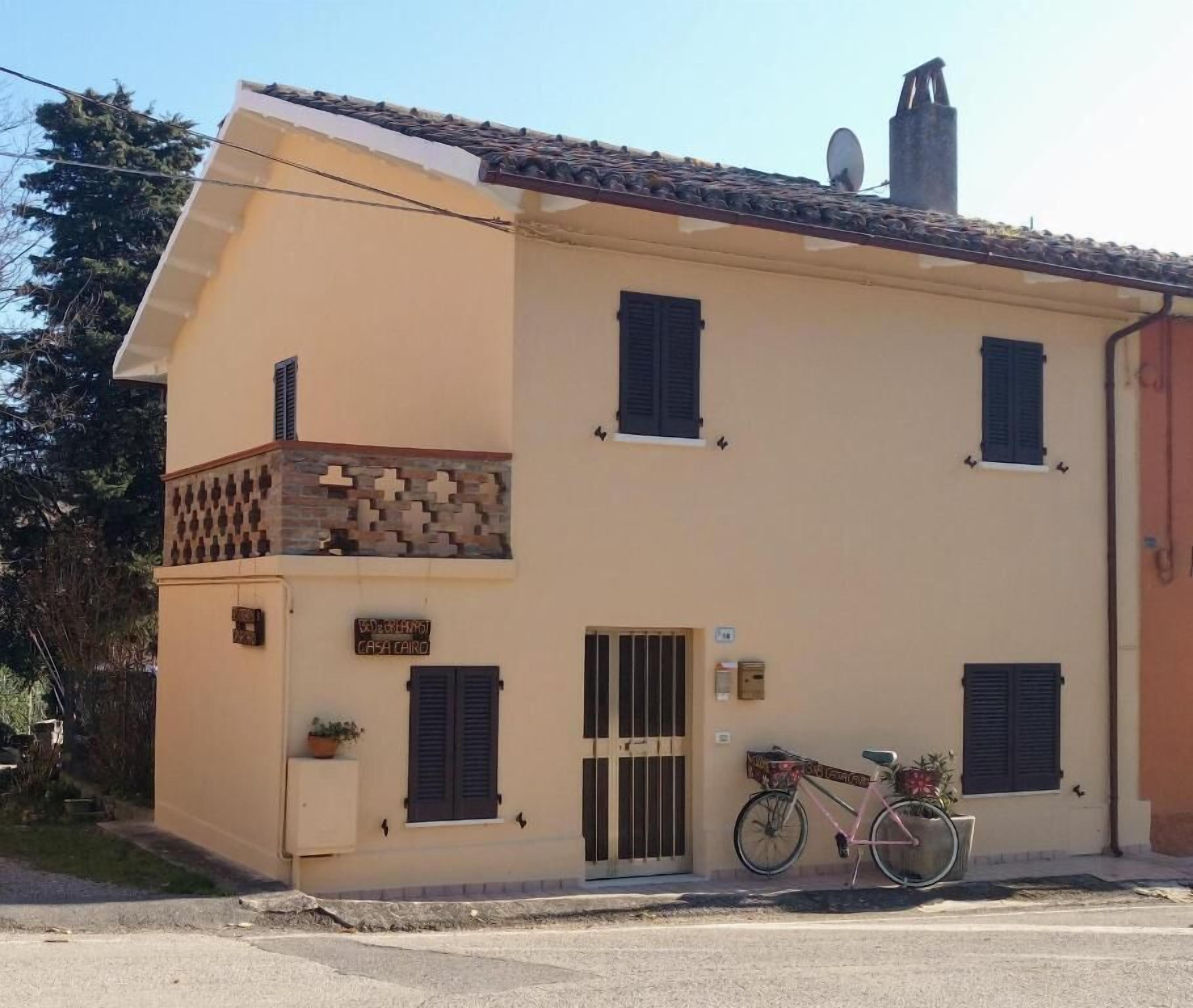 A two-story building with a balcony, a bicycle parked outside, and a sign indicating a business on the ground floor.