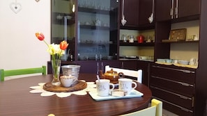 A dining table with a tea set, a vase with flowers, and a cabinet with glassware. - Casa Cairo Affittacamere (Mombaroccio)